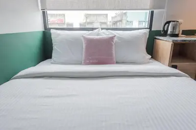 a white bed with a pink pillow on it at Swing & Pillows - Kentomen Hotel, Bamboo Hills in Kuala Lumpur
