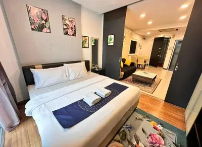 a bedroom with a large bed and a living room at Taragon Puteri Bintang KLCC View Studio Apartment in Kuala Lumpur