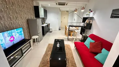 a living room with a red couch and a flat screen tv at Taragon Putri Bintang in Kuala Lumpur