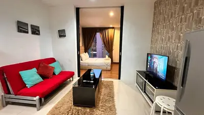 a living room with a red couch and a tv at Taragon Putri Bintang in Kuala Lumpur