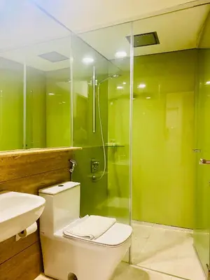 a green bathroom with a toilet and a shower at Kuala Lumpur Sky Suites KLCC in Kuala Lumpur