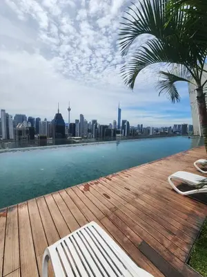 a pool with a palm tree and a view of a city at Infinity Pool Hostel KL in Kuala Lumpur