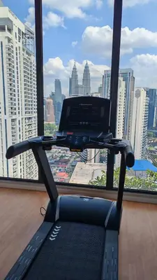 a treadmill in front of a window with a view of a city at Majestic Residence Suites KLCC by Homebrickz in Kuala Lumpur