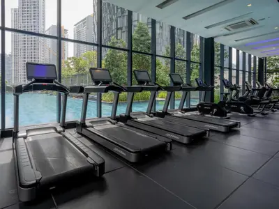 a row of treadmills in a gym with windows at Star KLCC Comfort Suite 3-4pax in Kuala Lumpur