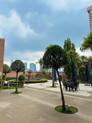 a park with a bench and trees and blue umbrellas at City view Service Residence At Times Square kL in Kuala Lumpur