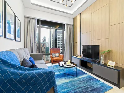 a living room with a blue couch and a tv at Leo Guesthouse at Anggun Residence Suite in Kuala Lumpur