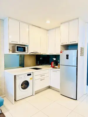 a kitchen with white cabinets and a washer and dryer at The Mercu Summer Suites By Skyline in Kuala Lumpur