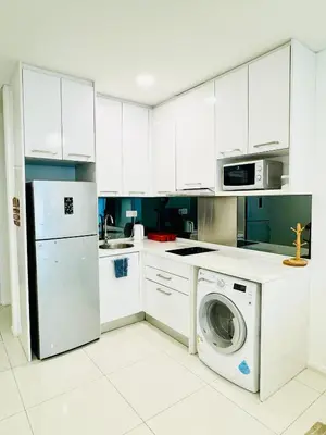 a kitchen with white cabinets and a washing machine at The Mercu Summer Suites By Skyline in Kuala Lumpur