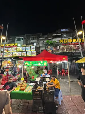 a man sitting at a food stand at night at SS Grey House Bukit Bintang KL in Kuala Lumpur
