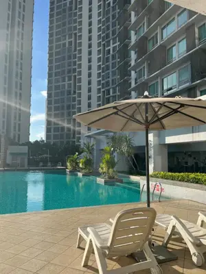 an umbrella and chairs next to a swimming pool at Stay Haven at Swiss Garden in Kuala Lumpur
