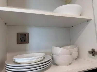 a pile of white plates and bowls on a shelf at Newly Renovated 3 Bedroom Vortex Suites KLCC by Tharwa in Kuala Lumpur