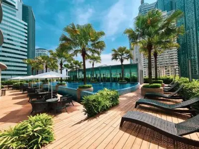 a pool with benches and palm trees in a city at Newly Renovated 3 Bedroom Vortex Suites KLCC by Tharwa in Kuala Lumpur