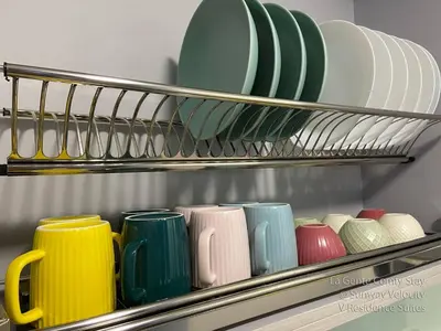 a group of plates and bowls on a shelf at La Gente Comfy Stay 2R2B Velocity - KL City View in Kuala Lumpur