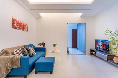 a living room with a blue couch and a tv at Carlton, Chelsea by COBNB, Sri Hartamas, Kuala Lumpur in Kuala Lumpur