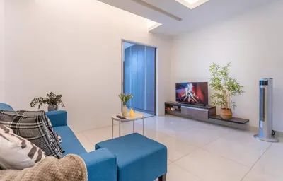 a living room with a blue couch and a tv at Carlton, Chelsea by COBNB, Sri Hartamas, Kuala Lumpur in Kuala Lumpur