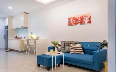 a living room with a blue couch and a kitchen at Carlton, Chelsea by COBNB, Sri Hartamas, Kuala Lumpur in Kuala Lumpur
