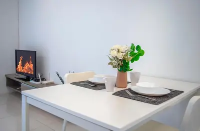 a white table with two plates and a vase with flowers at Carlton, Chelsea by COBNB, Sri Hartamas, Kuala Lumpur in Kuala Lumpur