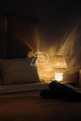 a person laying on a bed next to a lamp at Dorsett Hartamas KL, Bathtub Smart TV & WiFi in Kuala Lumpur