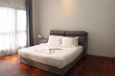 a bedroom with a bed with white sheets and a window at KLCC Sky Villa Suites The Mews in Kuala Lumpur