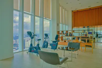 a gym with chairs and a table and windows at The Platinum KLCC By Aura Suites in Kuala Lumpur