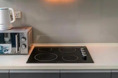a stove top oven sitting next to a microwave at Karaoke Party Penthouse at KL Gateway by Cobnb in Kuala Lumpur