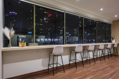 a bar with stools in front of a large window at KAĨTE Suites at Wisma Cosway Sky Bridge to Pavilion KL in Kuala Lumpur