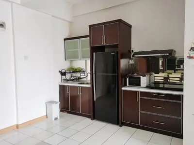 a kitchen with brown cabinets and a black refrigerator at Seri Bukit Ceylon in Kuala Lumpur