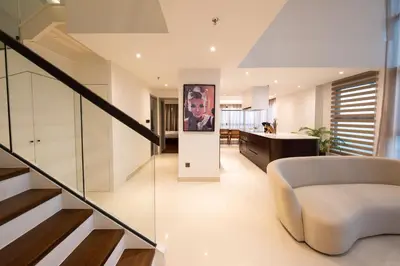 a living room with a staircase and a white couch at La Gente x Novo Ampang 3R3B Duplex Penthouse in Kuala Lumpur