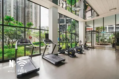 a gym with cardio equipment in a building with windows at Mont Kiara Ooak Suite Sunway 163 with Bathtub 2 Bed in Kuala Lumpur