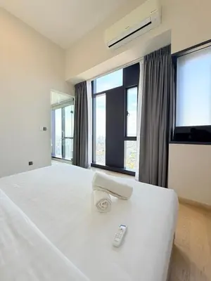 a bedroom with a white bed with a remote control on it at Star klcc by AR Accommodation in Kuala Lumpur