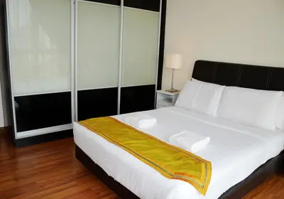 a bedroom with a large white bed with a yellow blanket at Taragon Residences in Kuala Lumpur