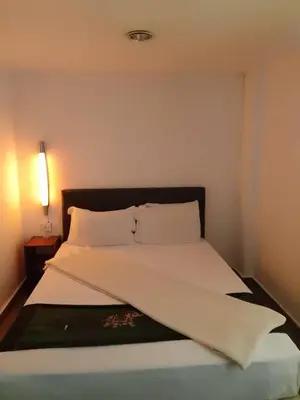 a bedroom with a bed with a white bedspread and a lamp at J Hotel Bukit Bintang in Kuala Lumpur
