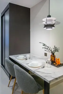 a dining room table with plates and chairs and aendant light at NOVO Ampang Modern Studio Infinity Pool near KLCC & Gleneagles in Kuala Lumpur