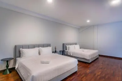 a bedroom with two beds with white sheets and wood floors at Embassy Villa by COBNB, Top Floor Unit at Ampang Hilir in Kuala Lumpur