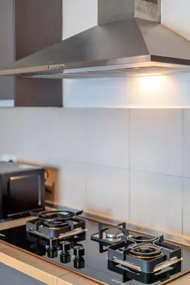 a kitchen with a stove top with a hood at Embassy Villa by COBNB, Top Floor Unit at Ampang Hilir in Kuala Lumpur