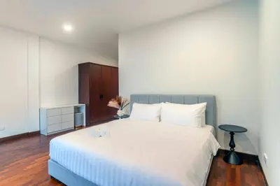a bedroom with a large white bed and a table at Embassy Villa by COBNB, Top Floor Unit at Ampang Hilir in Kuala Lumpur