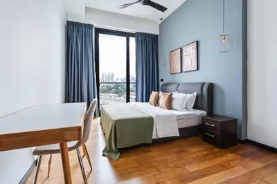 a bedroom with a bed with a desk and a window at Blueground Kuala Lumpur city view nr KL Bird Park KUL-2 in Kuala Lumpur