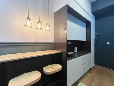 a kitchen with a counter with two stools and lights at The Colony By Infinitum Studio Room I in Kuala Lumpur