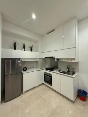 a kitchen with white cabinets and a stainless steel refrigerator at Lucentia Cozy Comfort Infinity Pool Suites in Kuala Lumpur