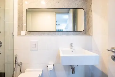 a white bathroom with a sink and a mirror at Isola KLCC By Feel Home in Kuala Lumpur