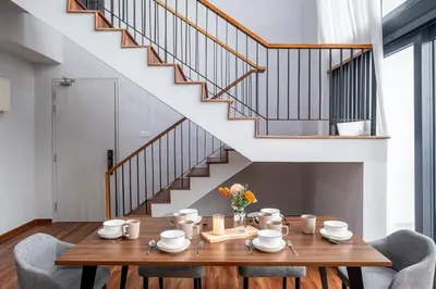 a dining room with a wooden table and a staircase at Isola KLCC By Feel Home in Kuala Lumpur