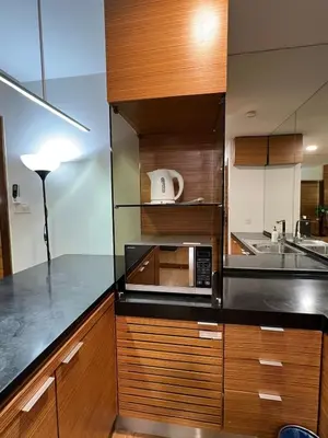 a kitchen with wooden cabinets and a microwave at Suit Unit at Dua Sentral in Kuala Lumpur