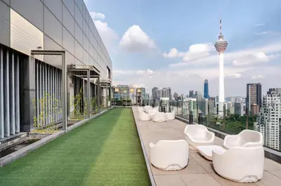 a balcony with white chairs and a view of the city at Luxury Living Hostel in Kuala Lumpur