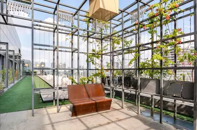 a bench in a glass greenhouse with plants at Luxury Living Hostel in Kuala Lumpur