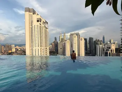 a man in a infinity pool with a city skyline at Majestic Suites KLCC By Fortune in Kuala Lumpur