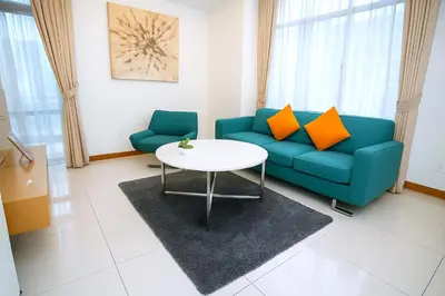 a living room with a blue couch and a table at Cormar Residences Kuala Lumpur in Kuala Lumpur