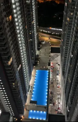 a large building with a blue pool in the middle at Warm & Spacious 2BR Apartment in Kuala Lumpur