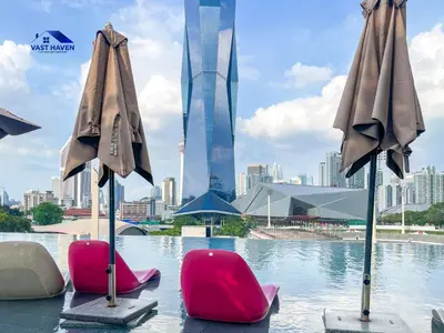 two chairs and umbrellas in a pool with a city at OPUS Residences Kuala Lumpur by VastHaven in Kuala Lumpur