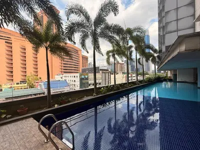 a swimming pool with palm trees on a building at Mykl Family suite Taragon in Kuala Lumpur