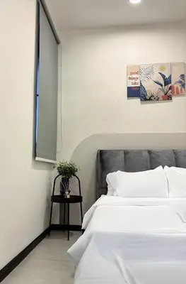 a bedroom with a bed with white sheets and a table at Neu Suites Apartments by LammyNora in Kuala Lumpur